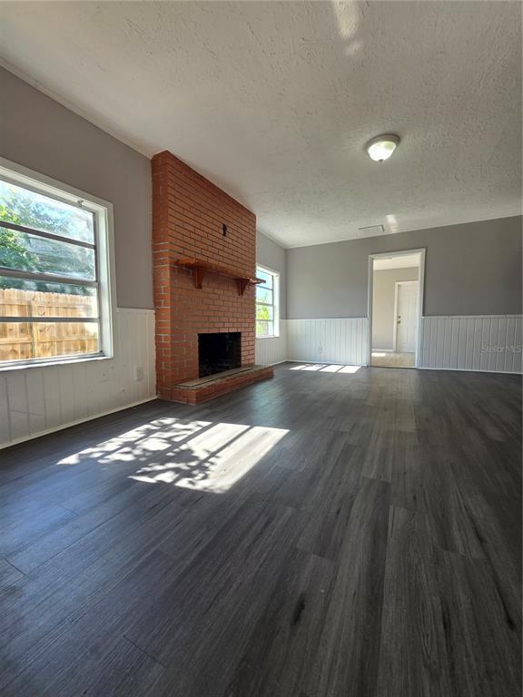 A living room features a red brick fireplace, white wainscoting, and dark wood-look flooring — 209 W KIRBY STREET, TAMPA, FL