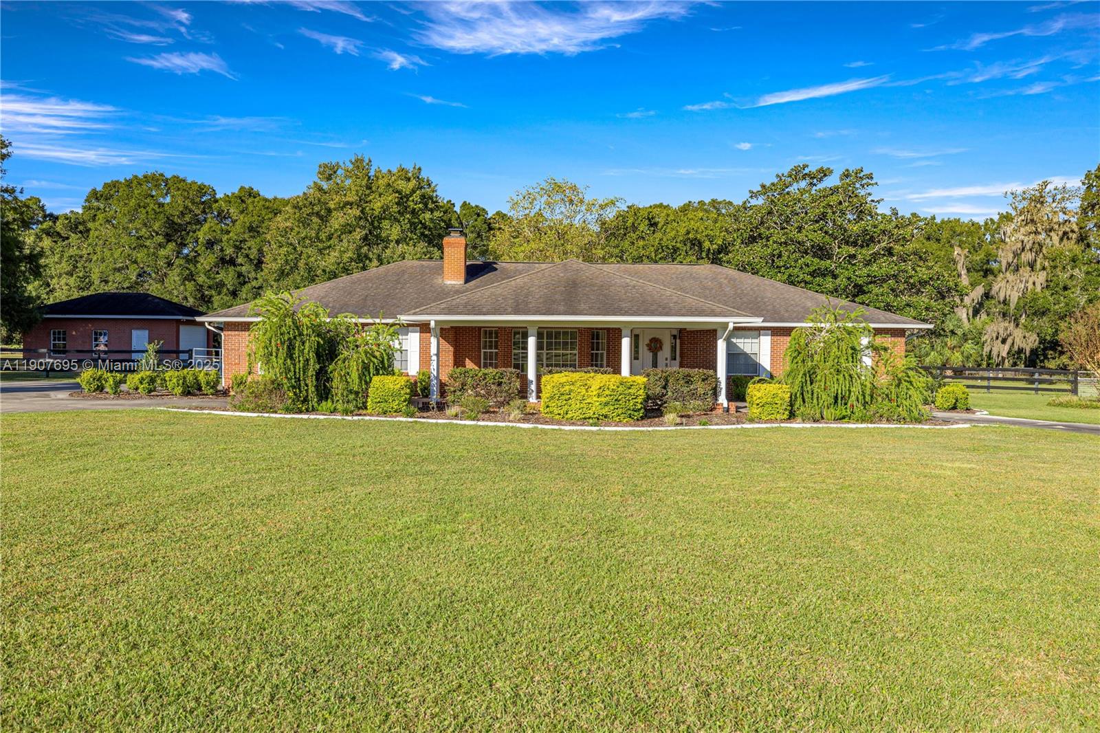 A single-story brick house with a covered porch sits behind a large green lawn — 9812 SW 74 Ave, Ocala FL 34476, OCALA, FL