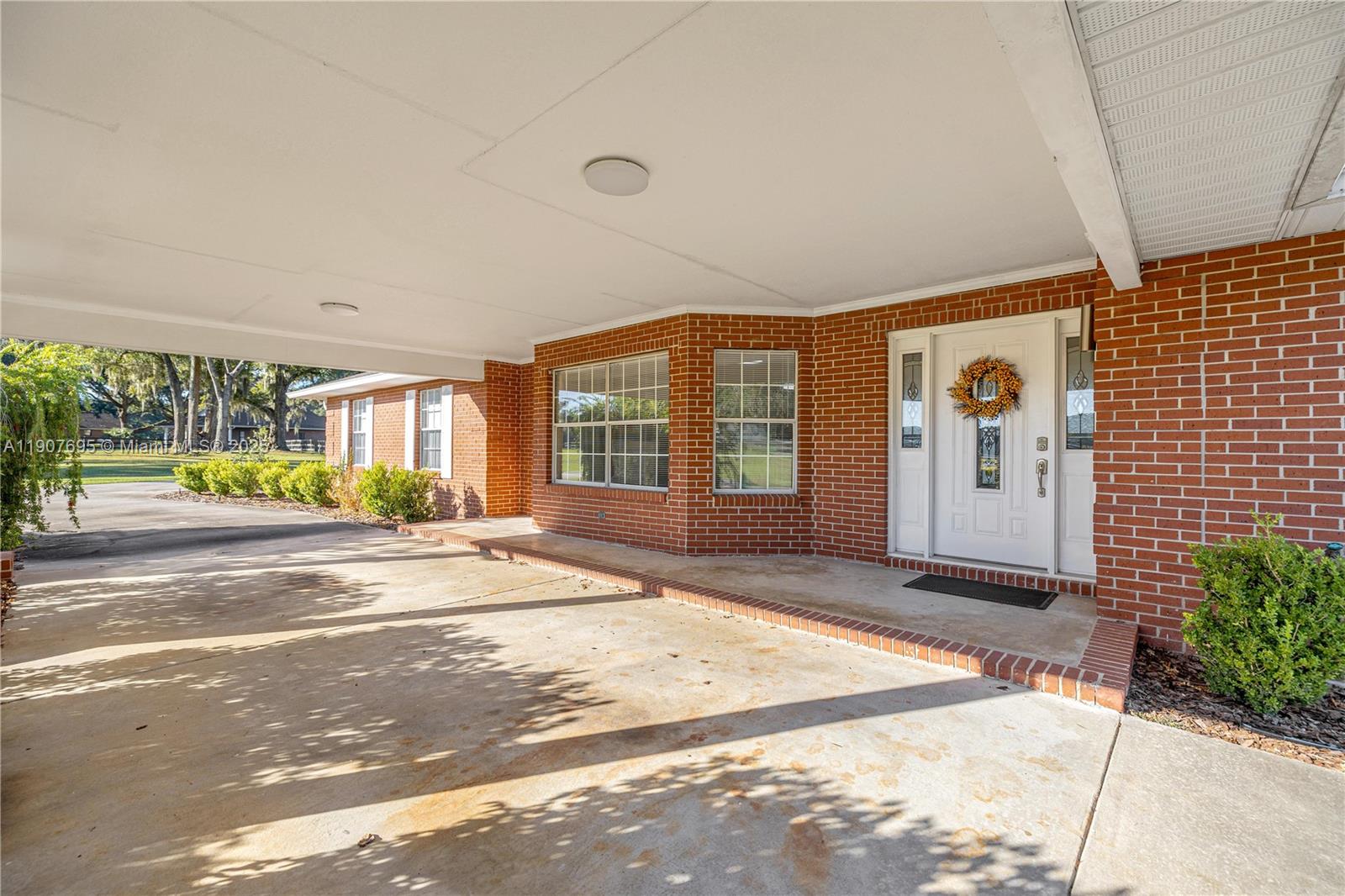 A brick house exterior features a covered carport and a white front door with wreath — 9812 SW 74 Ave, Ocala FL 34476, OCALA, FL