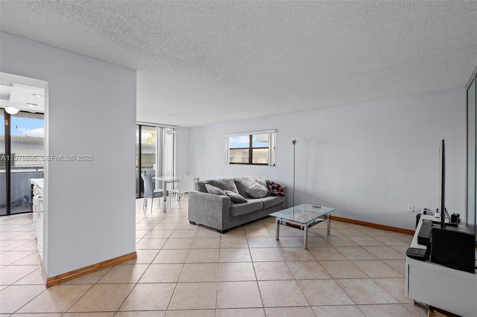 A living room with tile flooring, a gray sofa, and a glass coffee table — 7300 Wayne Ave # 217, Miami Beach FL 33141, MIAMI BEACH, FL