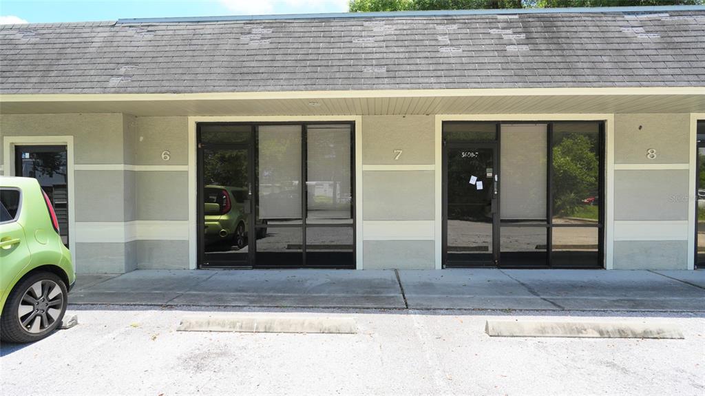 The exterior of a commercial building features three numbered glass-front units under a shingled roof — 5650 PARK BOULEVARD N UNIT 6, PINELLAS PARK, FL