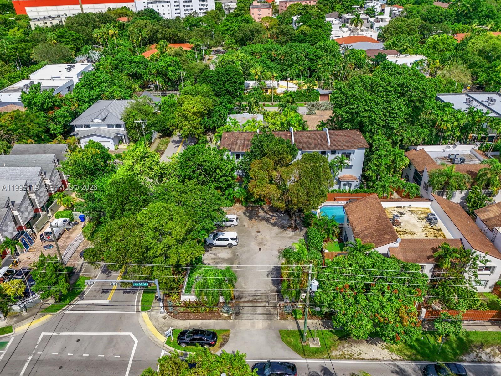 An aerial view shows a residential property with a parking lot, pool, and surrounding trees — 2987 Bird Ave, Miami FL 33133, MIAMI, FL