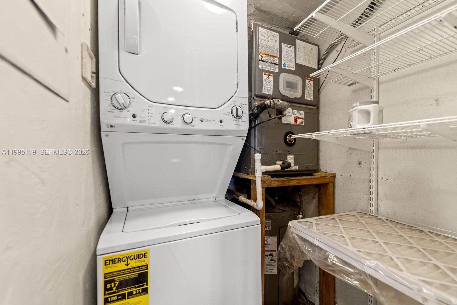 A laundry closet contains a stacked washer-dryer unit next to a water heater and shelving — 2987 Bird Ave, Miami FL 33133, MIAMI, FL