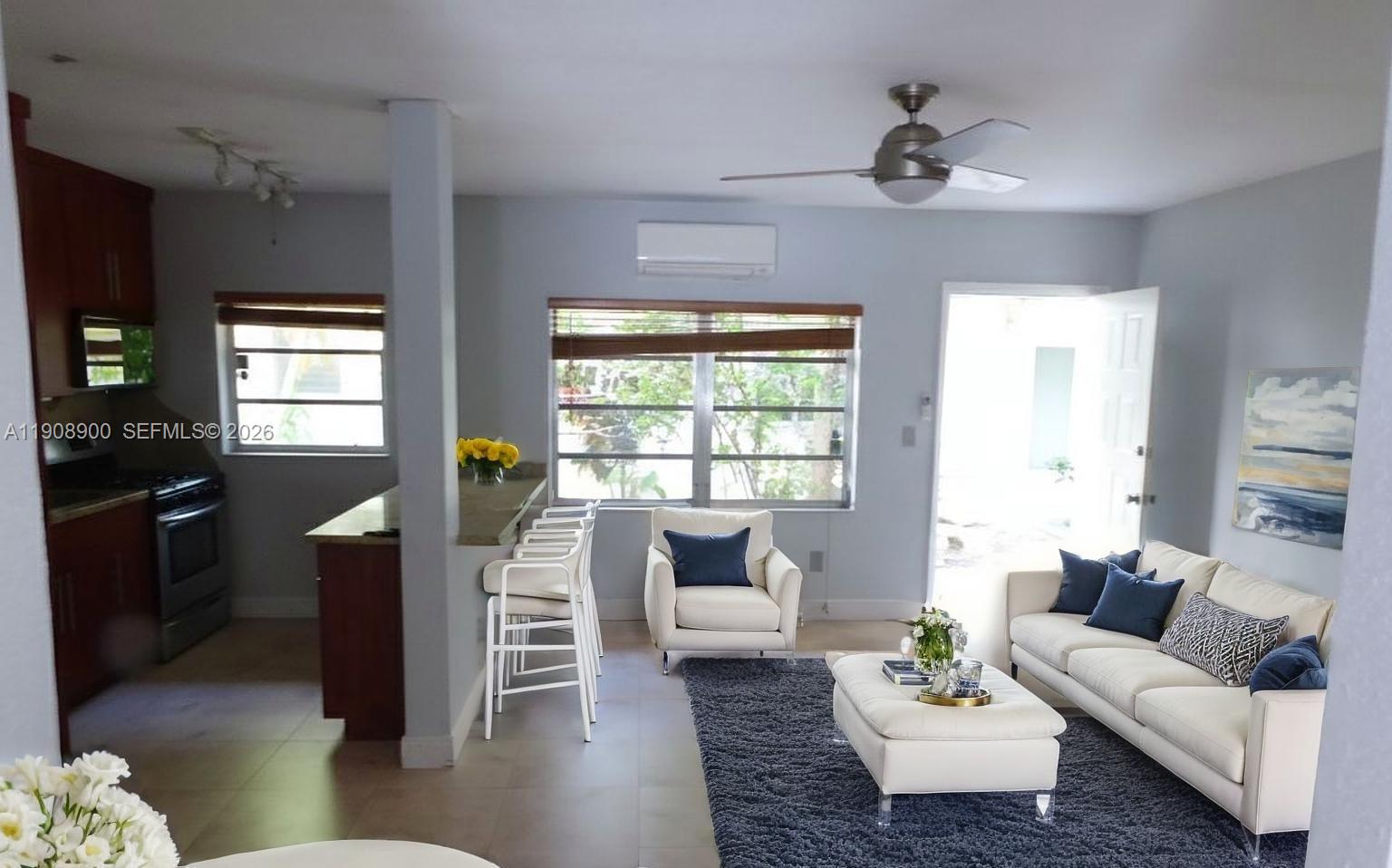 An open-concept living room and kitchen area with white furniture and a dark rug — 101 Collins Ave # 2, Miami Beach FL 33139, MIAMI BEACH, FL