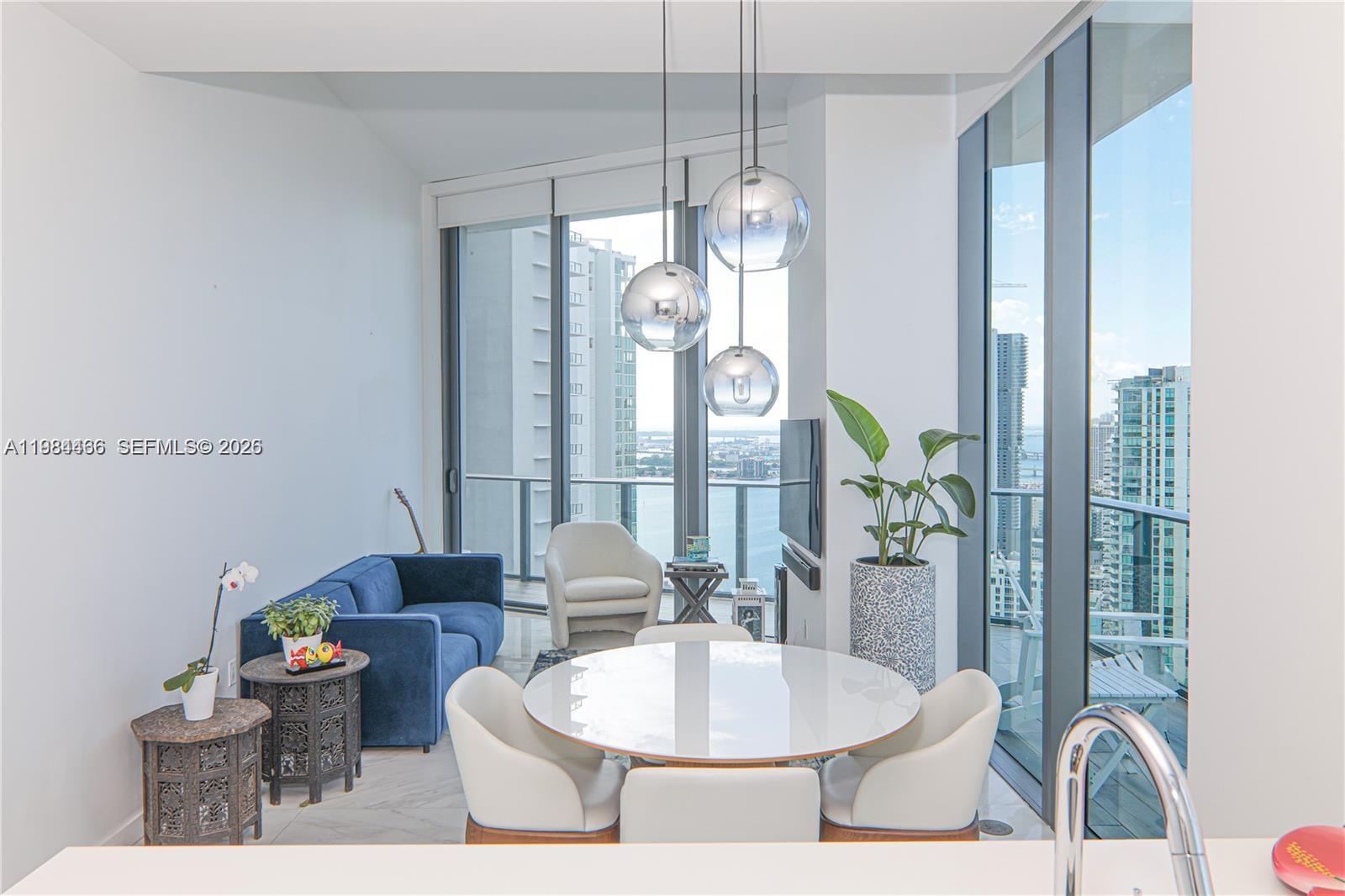 A modern dining and living area features floor-to-ceiling windows with expansive city and water views — 501 NE 31st St # 4008, Miami FL 33137, MIAMI, FL