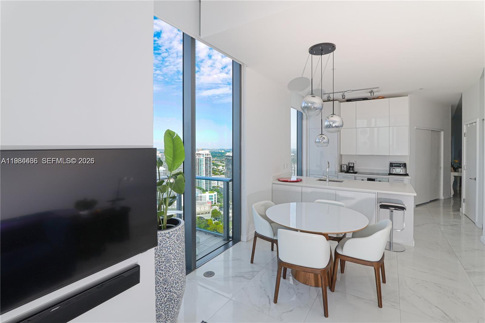 A modern kitchen and dining area features white cabinetry, marble floors, and floor-to-ceiling windows — 501 NE 31st St # 4008, Miami FL 33137, MIAMI, FL