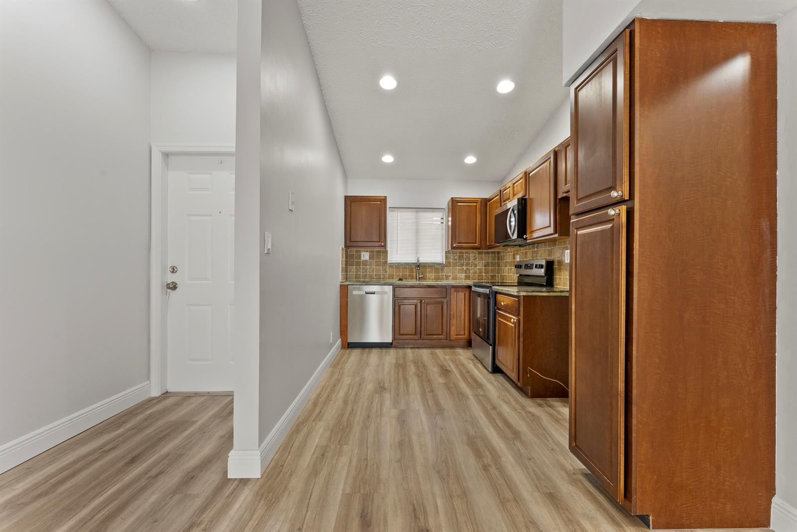 A kitchen features wood cabinets, stainless steel appliances, and light wood-look flooring — 2900 Olivewood Terrace # 201, Boca Raton FL 33431, BOCA RATON, FL