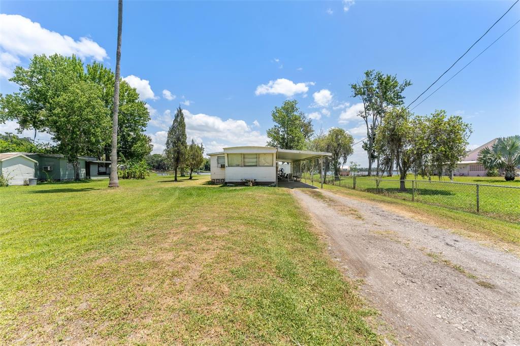 A single-story mobile home with a carport sits on a grassy lot with a driveway — 7558 BERKLEY ROAD, POLK CITY, FL