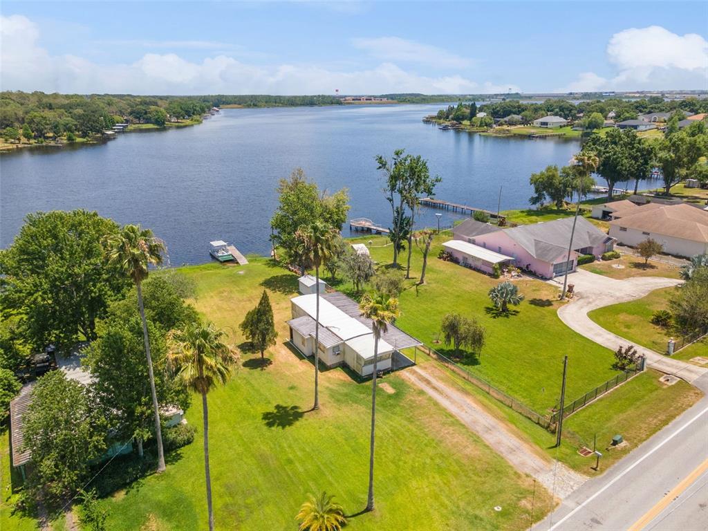 An aerial view shows a waterfront property with two houses, palm trees, and a dock — 7558 BERKLEY ROAD, POLK CITY, FL