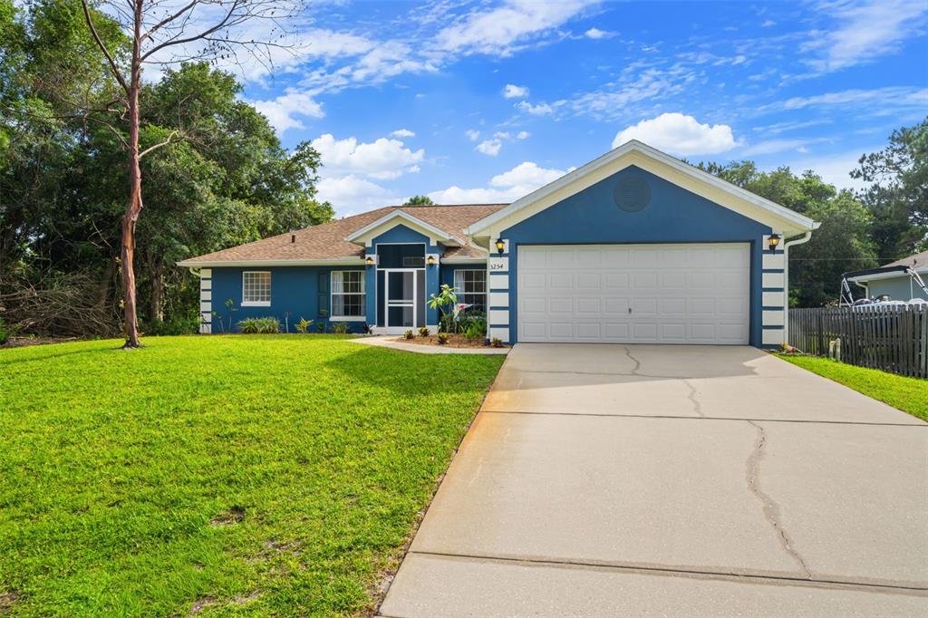 A blue single-story house with a two-car garage and a concrete driveway — 3254 WASILLA AVENUE SE, PALM BAY, FL