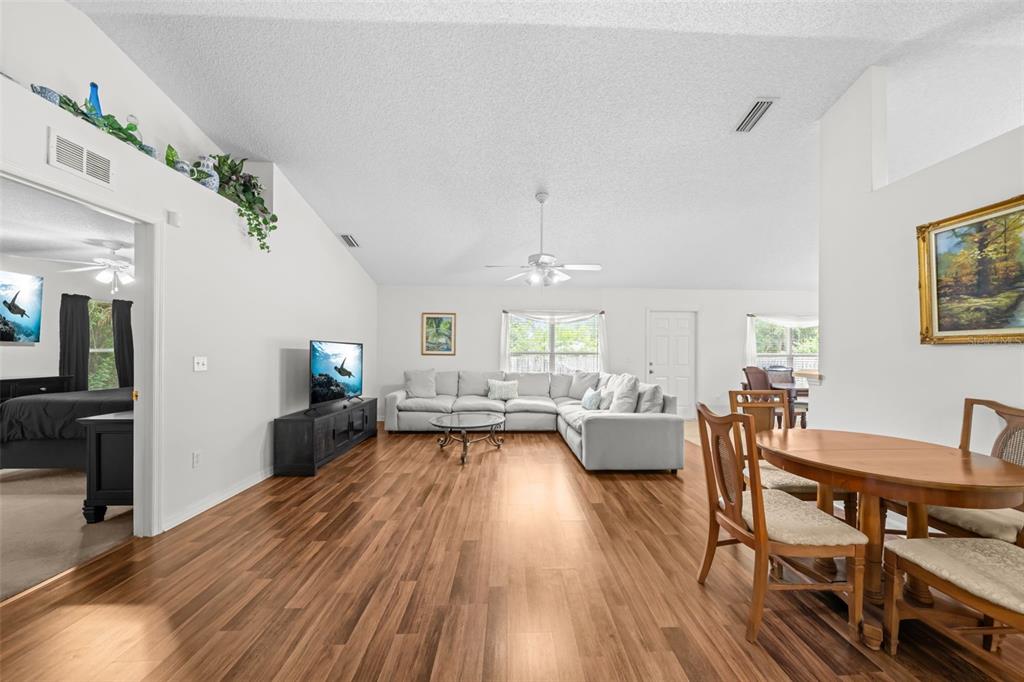 A living room with wood-look flooring, a sectional sofa, and a dining area — 3254 WASILLA AVENUE SE, PALM BAY, FL