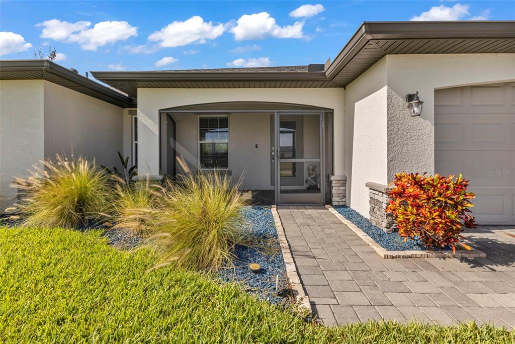 A paved walkway leads to the screened front entryway of a single-story stucco home — 2926 NW 25TH STREET, CAPE CORAL, FL
