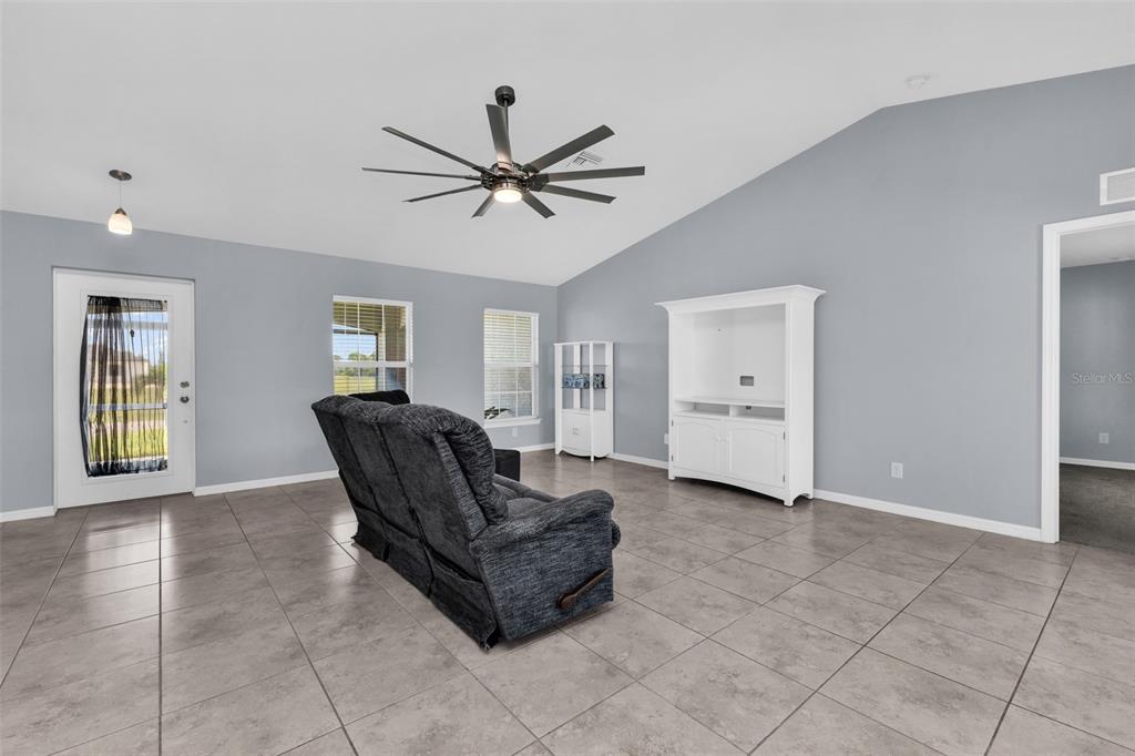 A living room features gray walls, large floor tiles, a ceiling fan, and a white cabinet — 2926 NW 25TH STREET, CAPE CORAL, FL