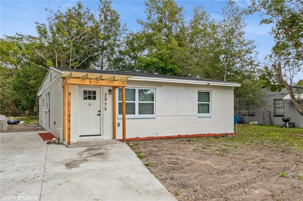 A small, white, single-story house features a wooden pergola over the front entrance — 3935 WELLS STREET, ORLANDO, FL