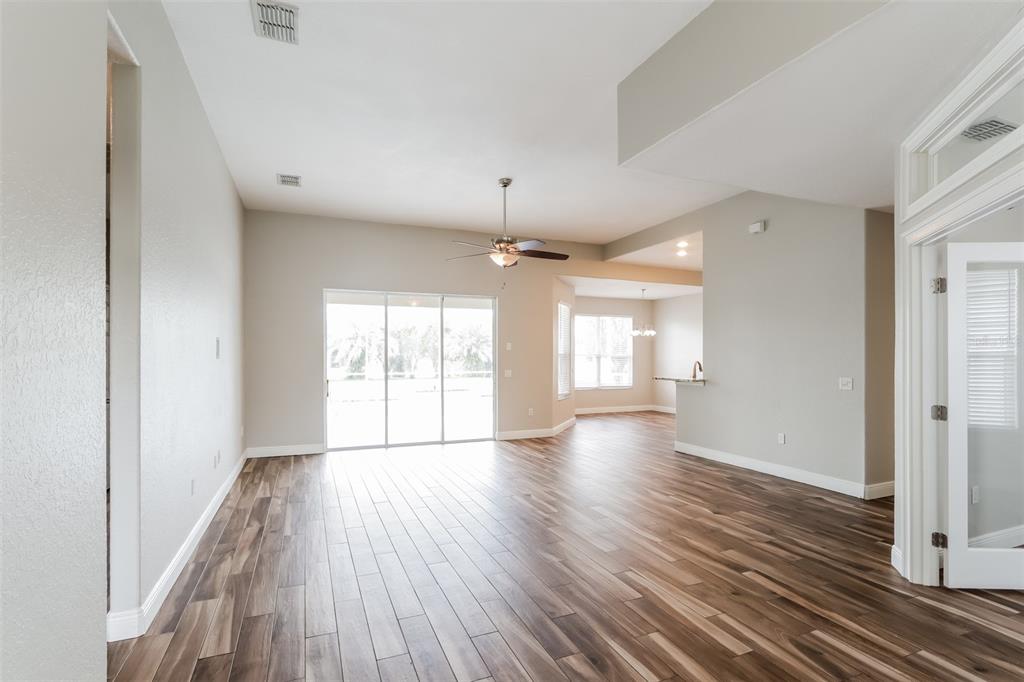 An open-concept living area features wood-look tile flooring, a ceiling fan, and sliding glass doors — 2954 DUNHILL CIRCLE, LAKELAND, FL