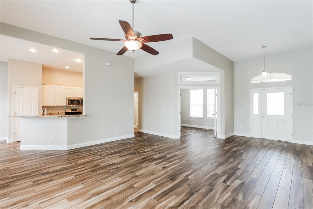 An open-concept living area features wood-look tile flooring, a ceiling fan, and an adjacent kitchen — 2954 DUNHILL CIRCLE, LAKELAND, FL