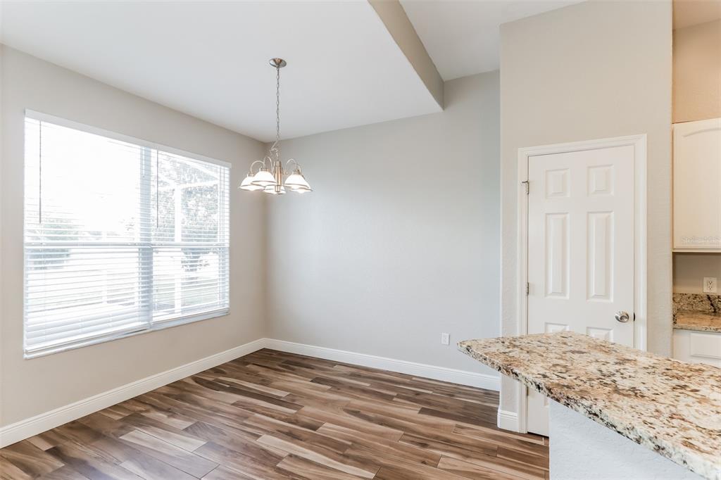 A dining area with wood-look flooring, a chandelier, a window with blinds, and granite countertops — 2954 DUNHILL CIRCLE, LAKELAND, FL