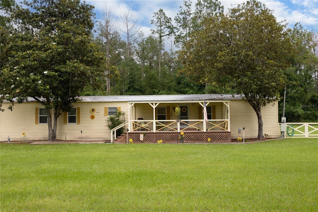 A single-story manufactured home with a front porch sits on a grassy lot — 229 SW BARWICK TERRACE, LAKE CITY, FL