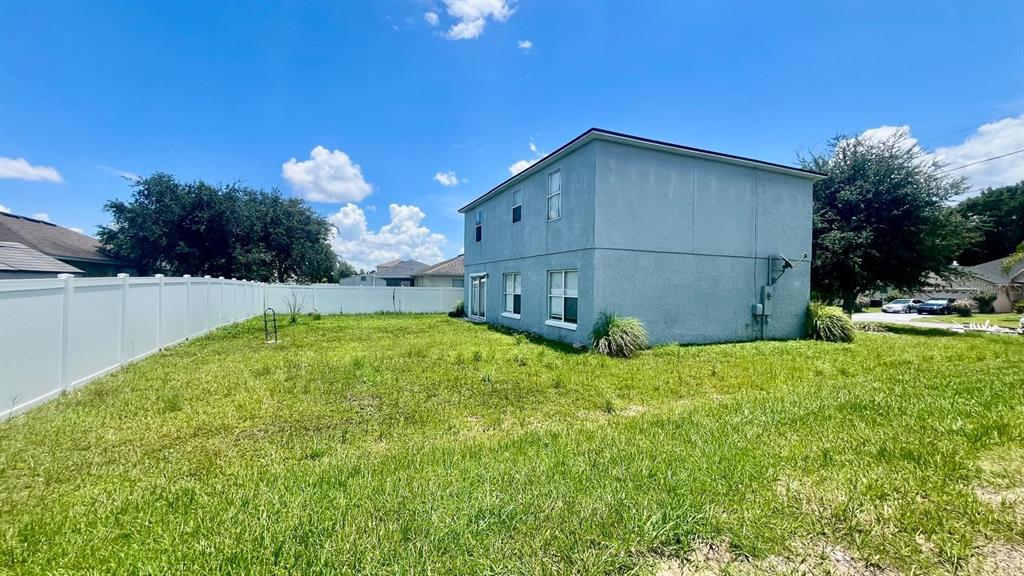 A two-story house with a light blue exterior stands in a large, grassy backyard — 703 ROBIN COURT, KISSIMMEE, FL