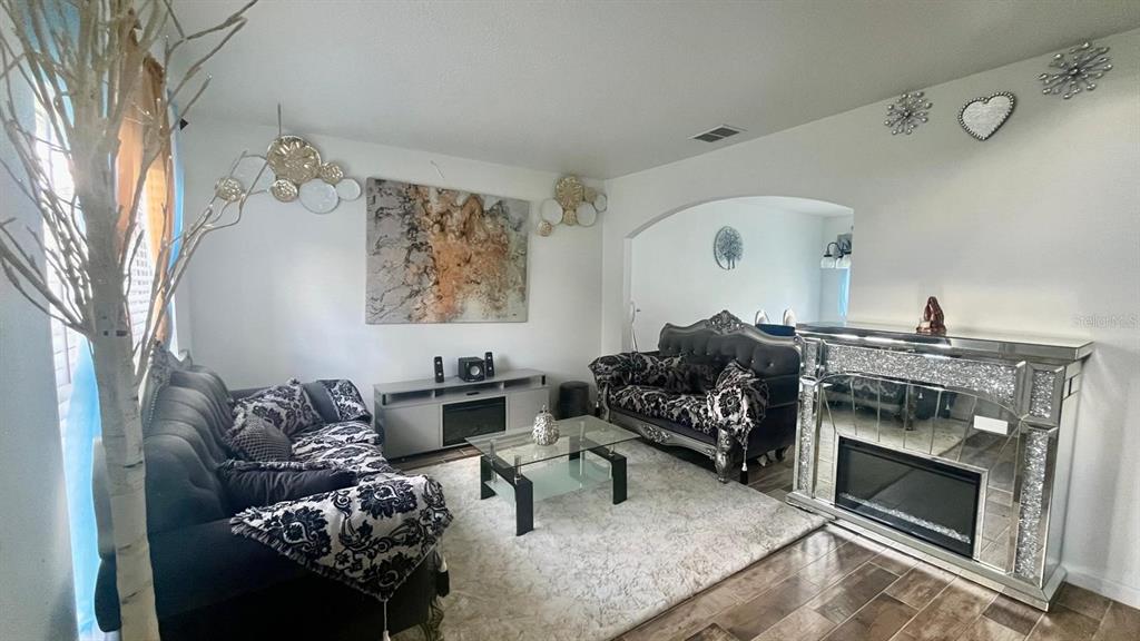 A living room features two dark sofas, a glass coffee table, and a mirrored fireplace — 703 ROBIN COURT, KISSIMMEE, FL