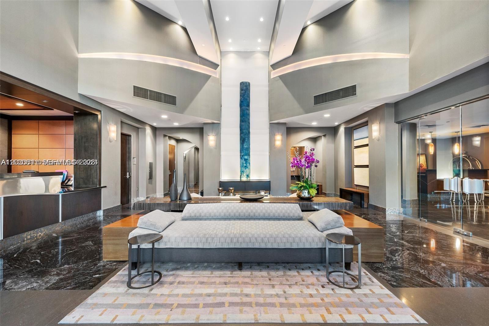 A modern lobby features high ceilings, a central sofa, and polished dark marble flooring — 9401 Collins Ave # 603, Surfside FL 33154, SURFSIDE, FL