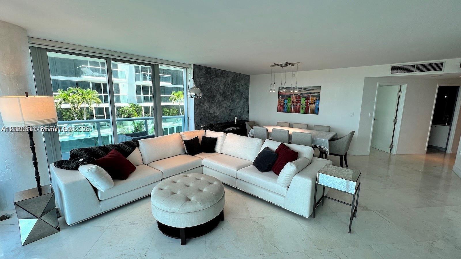 A modern living and dining area features a white sectional sofa, ottoman, and marble floors — 9401 Collins Ave # 603, Surfside FL 33154, SURFSIDE, FL