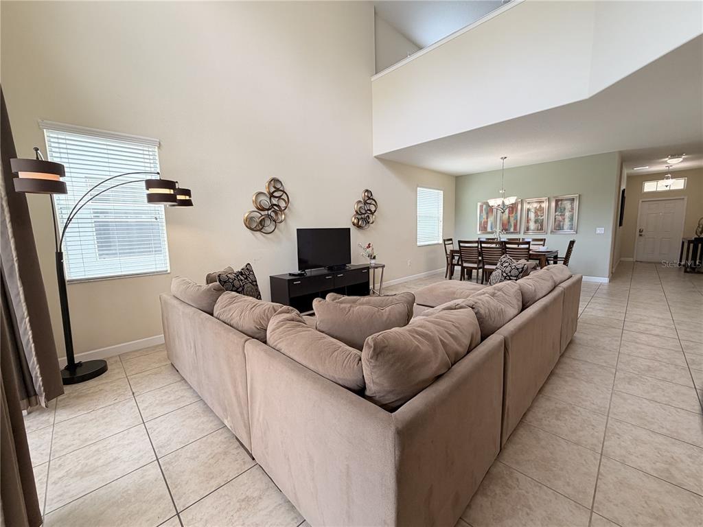 A living room with a large sectional sofa, television, and an adjacent dining area — 8954 SUGAR PALM ROAD UNIT 8954, KISSIMMEE, FL