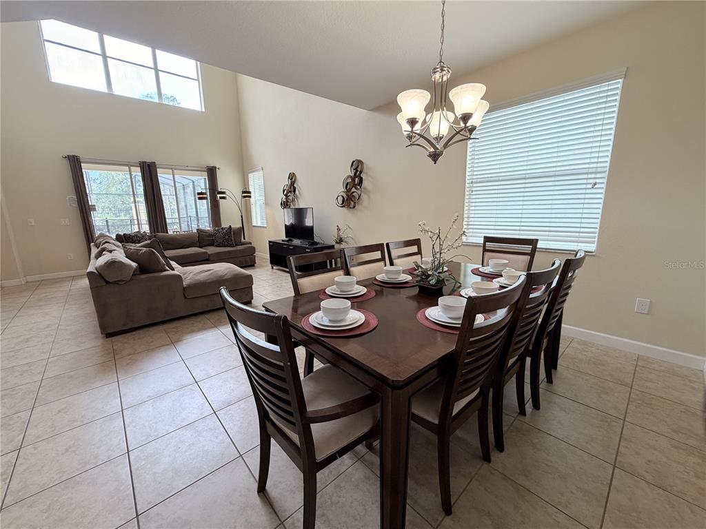 A dining area with a wooden table and chairs sits adjacent to a living room — 8954 SUGAR PALM ROAD UNIT 8954, KISSIMMEE, FL