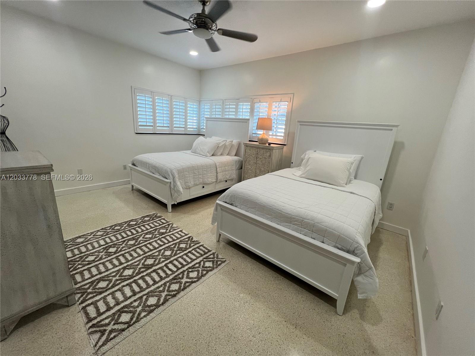A bedroom features two white beds, a patterned area rug, and white plantation shutters — 1100 NE 84th St, Miami FL 33138, MIAMI, FL