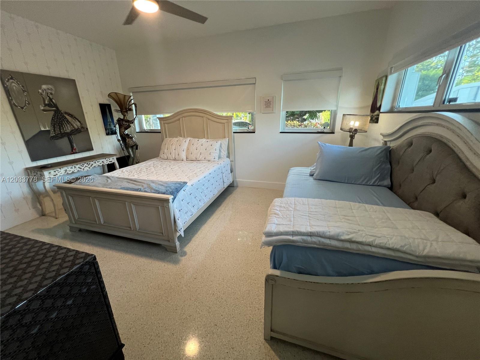 A bedroom features two beds, white walls, light-colored flooring, and a ceiling fan — 1100 NE 84th St, Miami FL 33138, MIAMI, FL