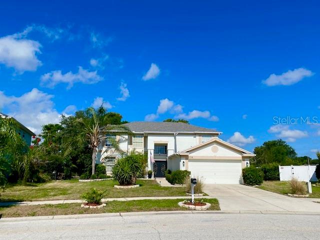 A two-story suburban house with a light-colored exterior, a palm tree, and a paved driveway — 11718 STONEWOOD GATE DRIVE, RIVERVIEW, FL