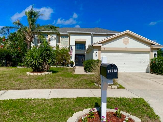 A two-story house with white stucco walls, a dark front door, and an American flag — 11718 STONEWOOD GATE DRIVE, RIVERVIEW, FL