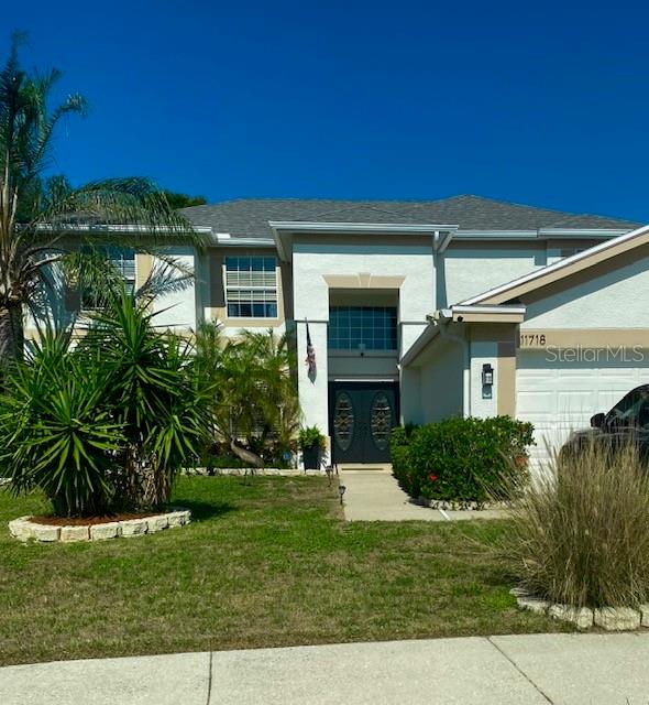 A two-story house exterior with a palm tree, an American flag, and double front doors — 11718 STONEWOOD GATE DRIVE, RIVERVIEW, FL