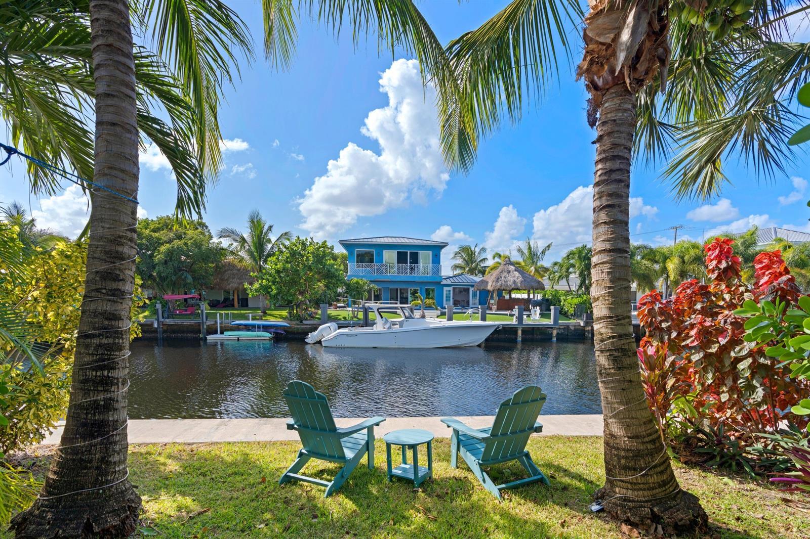 A waterfront view of a blue house with a boat docked in a canal — 391 SE 7th Avenue, Pompano Beach FL 33060, POMPANO BEACH, FL