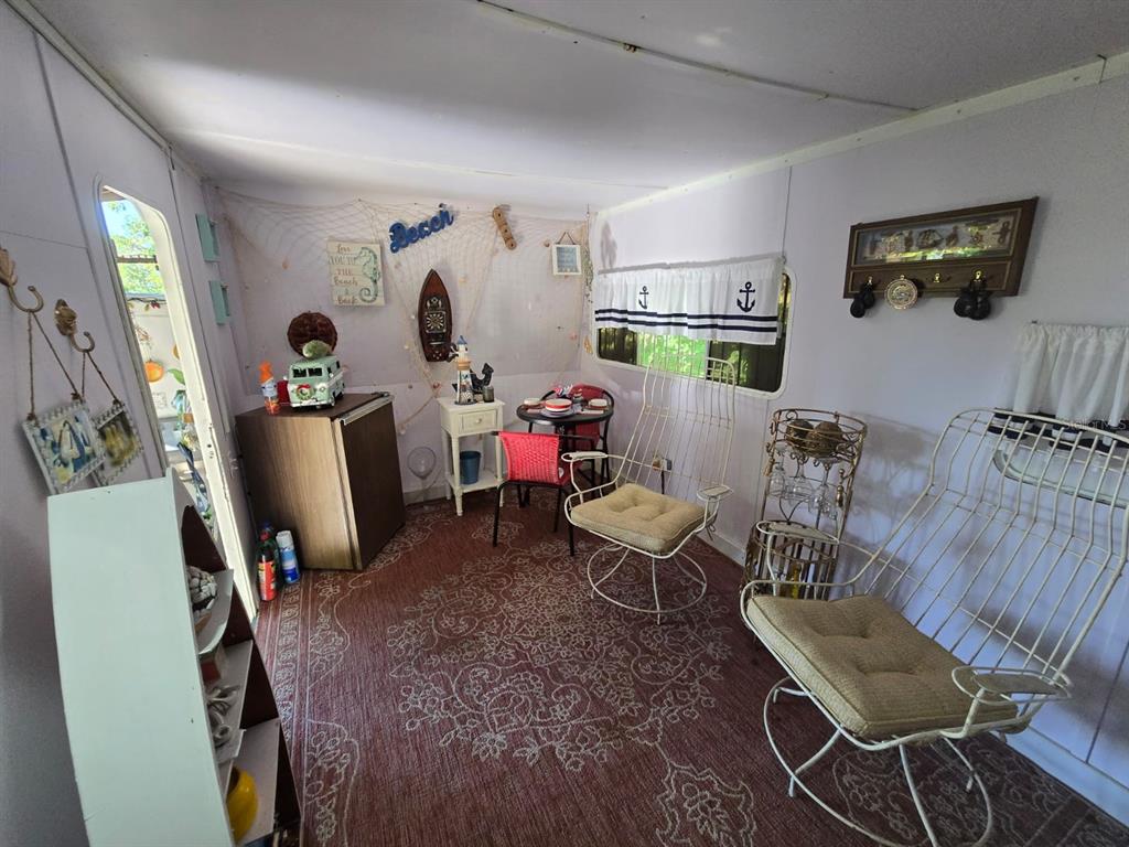 A sunroom features a patterned rug, two white metal chairs, a small table, and nautical decor — BO. LLANOS TUNA, SECTOR LAS MAGAS, CABO ROJO, PR