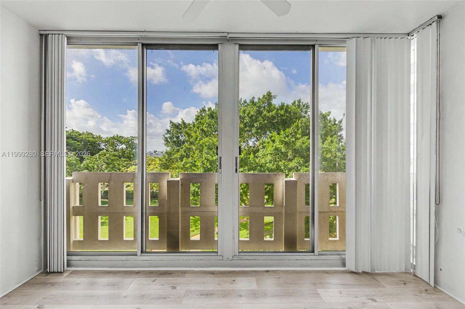 A room with light wood-look flooring features a large sliding glass door overlooking trees — 4330 Hillcrest Dr # 405, Hollywood FL 33021, HOLLYWOOD, FL