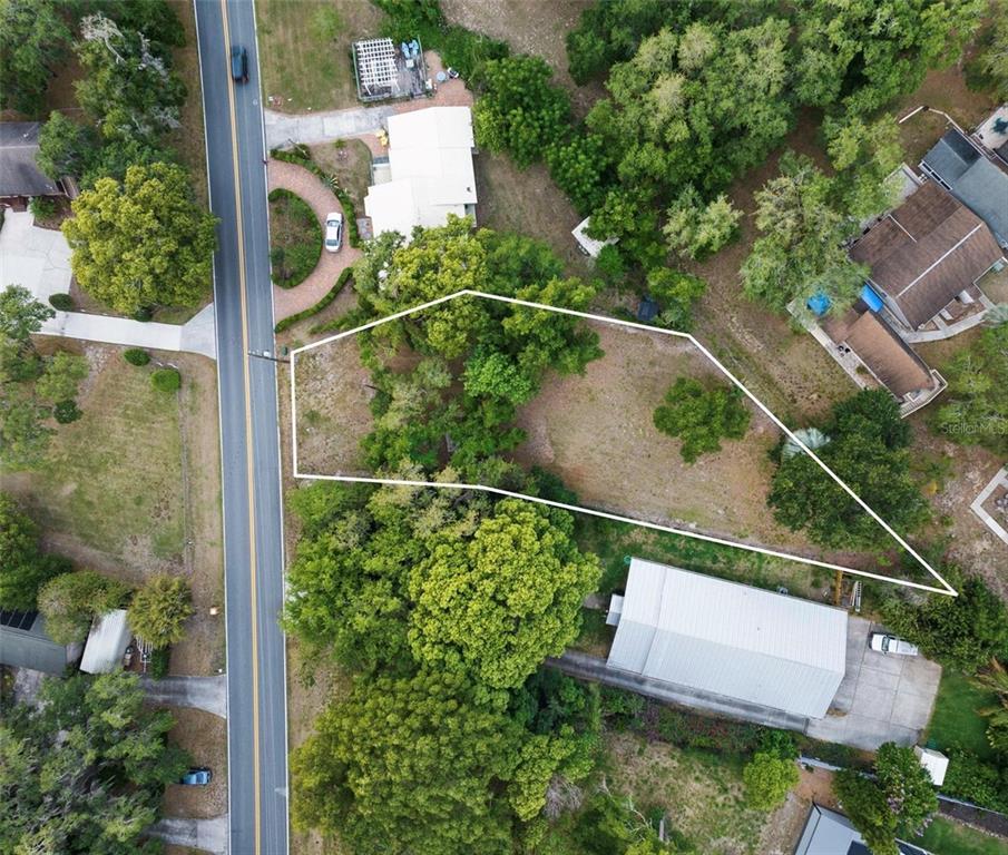 An aerial view shows a vacant, irregularly shaped lot outlined in white next to a road — LAKE LOUISA ROAD, CLERMONT, FL