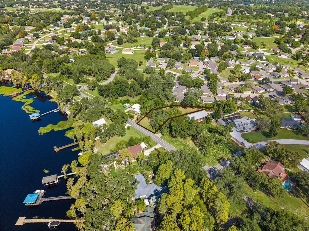 An aerial view shows a vacant, tree-covered lot outlined in brown near a lake — LAKE LOUISA ROAD, CLERMONT, FL