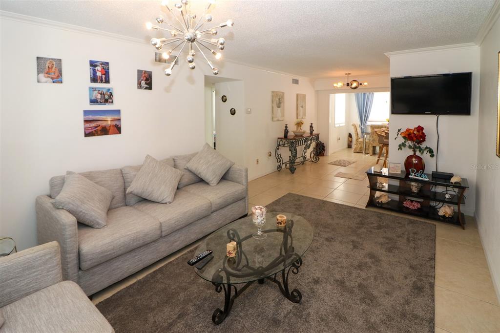 A living room features a gray sofa, glass coffee table, and a television mounted on wall — 4158 TAMIAMI TRAIL UNIT G1, PORT CHARLOTTE, FL
