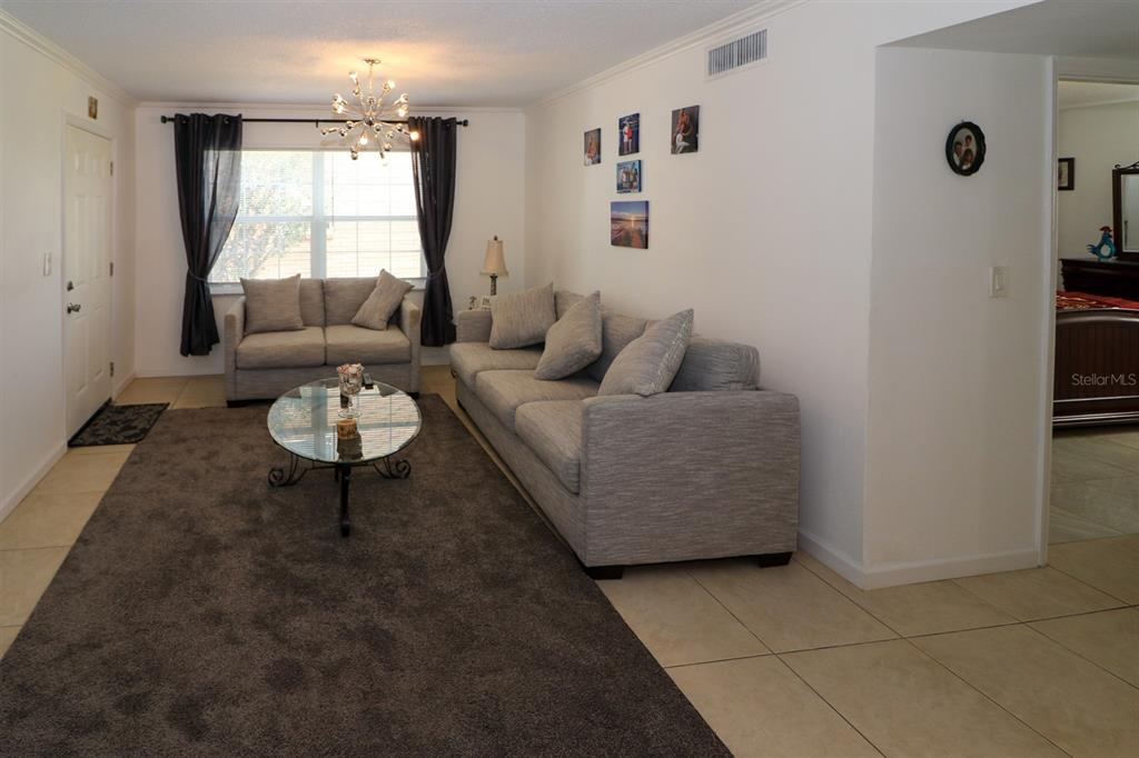 A living room features a gray sofa, a glass coffee table, and a dark area rug — 4158 TAMIAMI TRAIL UNIT G1, PORT CHARLOTTE, FL