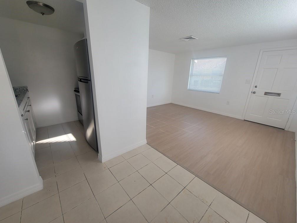 A kitchen with tiled floors transitions into a living area with light wood-look flooring — 4922 FILNER STREET, NEW PORT RICHEY, FL