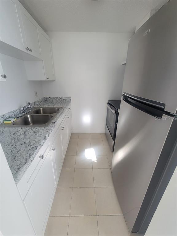 A galley kitchen features white cabinets, granite countertops, a double sink, and stainless steel appliances — 4922 FILNER STREET, NEW PORT RICHEY, FL
