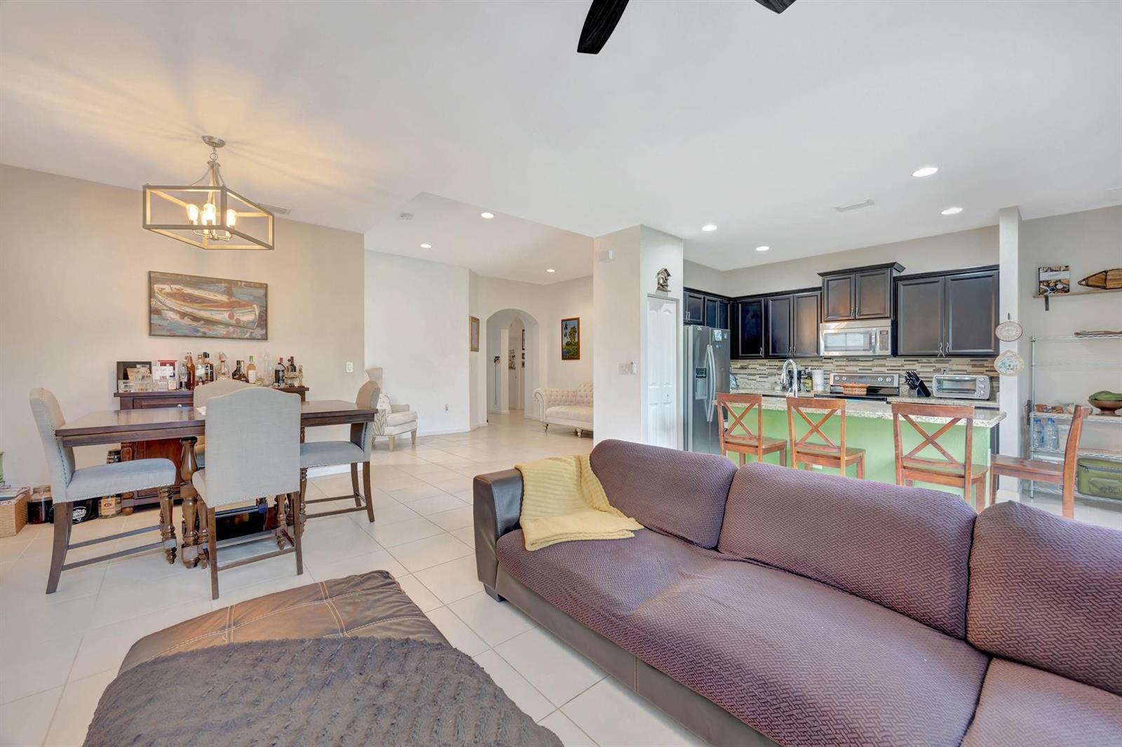 An open-concept living area features a kitchen with dark cabinets, a dining set, and sofa — 25123 SW 118th Place, Cutler Bay FL 33032, CUTLER BAY, FL