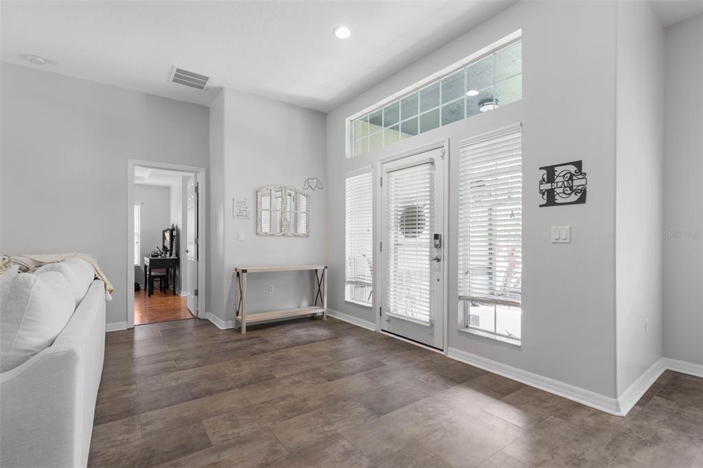 This entryway features light gray walls, dark wood-look tile flooring, and a glass-paneled front door — 51 BANNERWOOD LANE, PALM COAST, FL