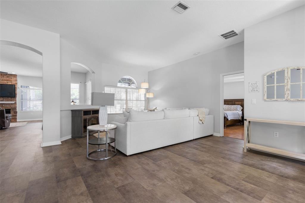 A living room with a white sectional sofa, wood-look flooring, and an arched wall opening — 51 BANNERWOOD LANE, PALM COAST, FL