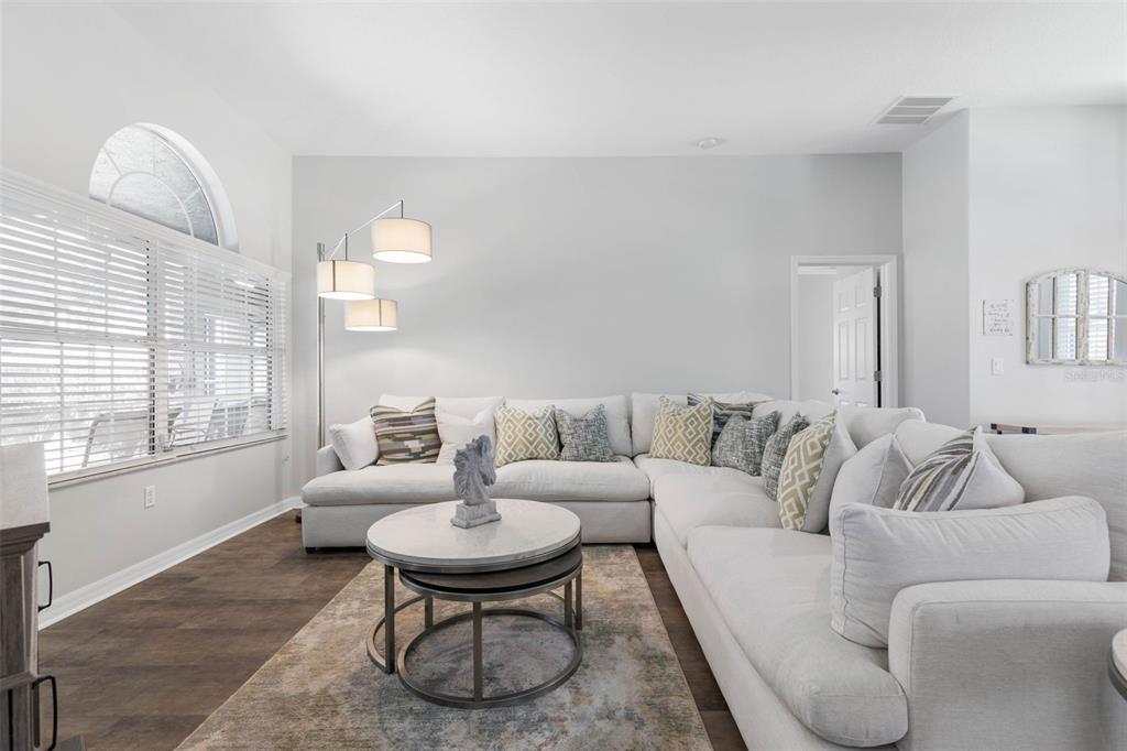 A living room features a large white sectional sofa, a round coffee table, and a floor lamp — 51 BANNERWOOD LANE, PALM COAST, FL