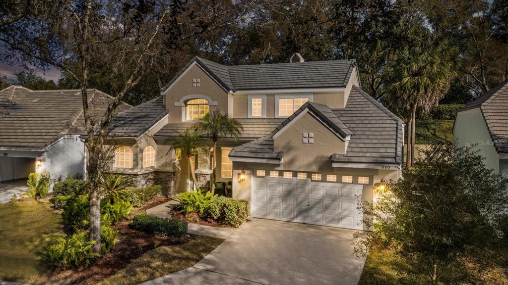 A two-story suburban house with a gray tile roof, beige stucco siding, and a garage — 220 WIMBLEDON CIRCLE, LAKE MARY, FL
