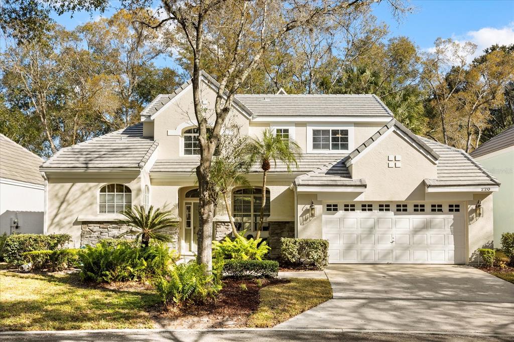 A two-story suburban house with a beige stucco exterior, stone accents, and a two-car garage — 220 WIMBLEDON CIRCLE, LAKE MARY, FL