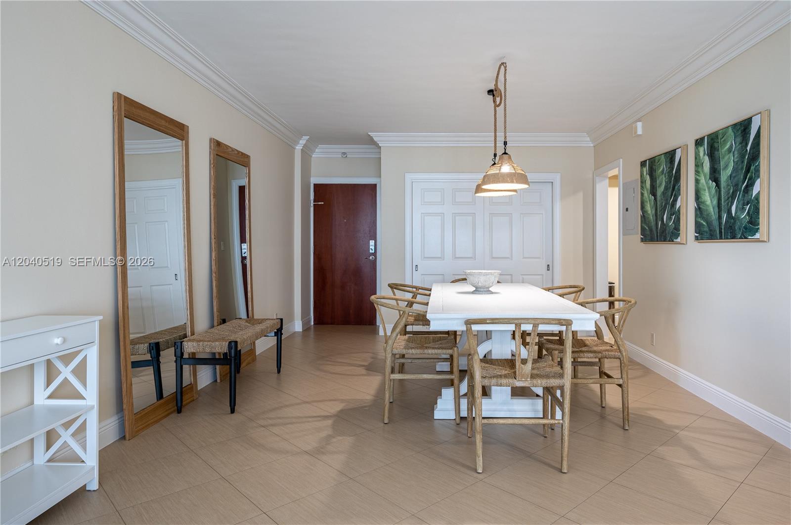A dining room features a white table, woven chairs, two mirrors, and tropical wall art — 4001 S Ocean Dr # 9J, Hollywood FL 33019, HOLLYWOOD, FL