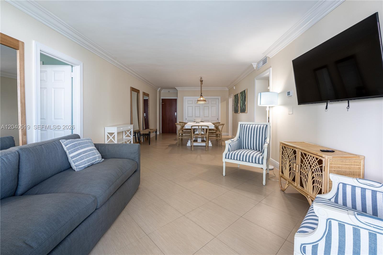 A living and dining area features a grey sofa, striped armchairs, and a wall-mounted television — 4001 S Ocean Dr # 9J, Hollywood FL 33019, HOLLYWOOD, FL